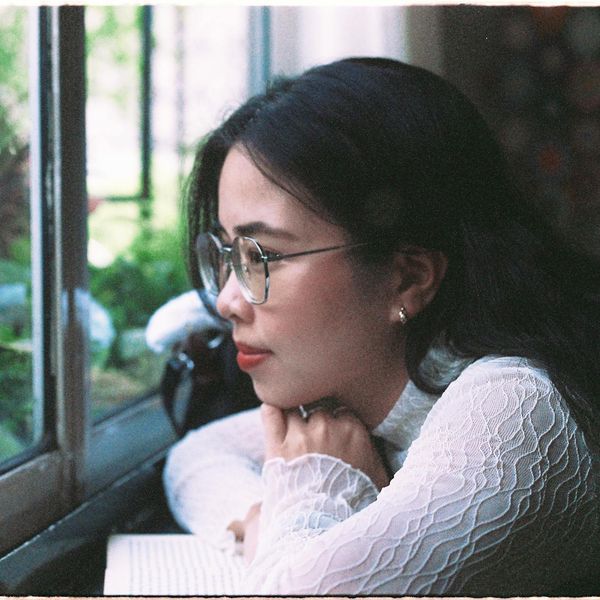Person meditatively looking out a window at a park